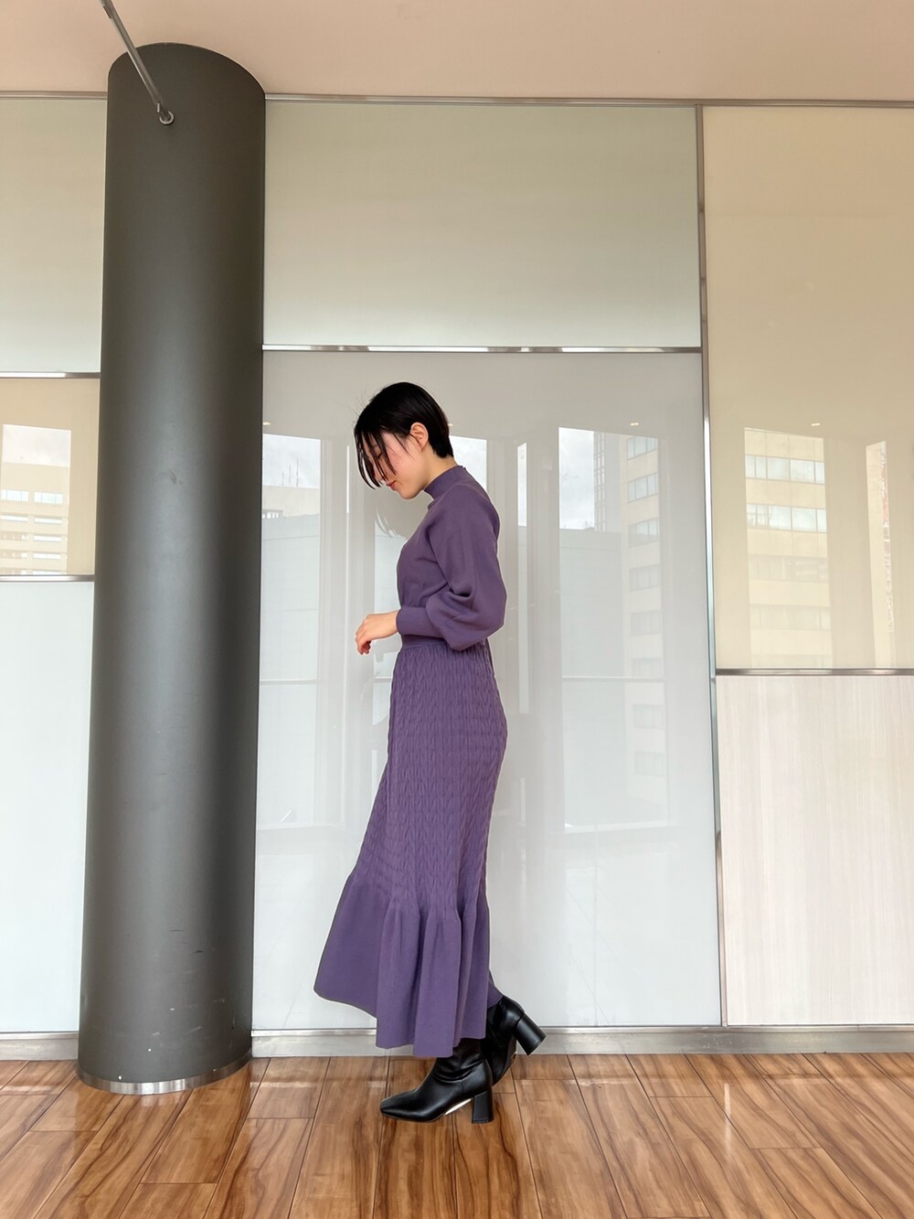 ブラック系のダウンジャケット/コート、ブラック系のブーツ、パープル系のワンピースを着用したレディースの冬コーディネートの8枚目の写真