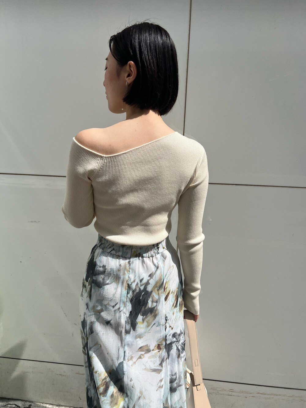 ホワイト系のパンプス、ベージュ系のハンドバッグ、ホワイト系のニット/セーターを着用したレディースの春コーディネートの9枚目の写真