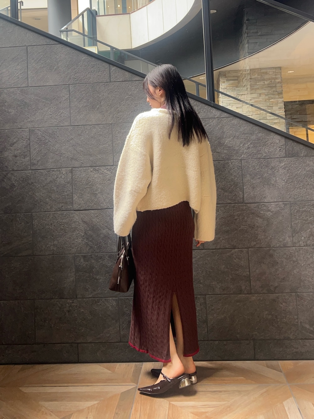 ホワイト系のカーディガン/ボレロ、ブラウン系のワンピース、ブラウン系のボストンバッグを着用したレディースの秋コーディネートの2枚目の写真