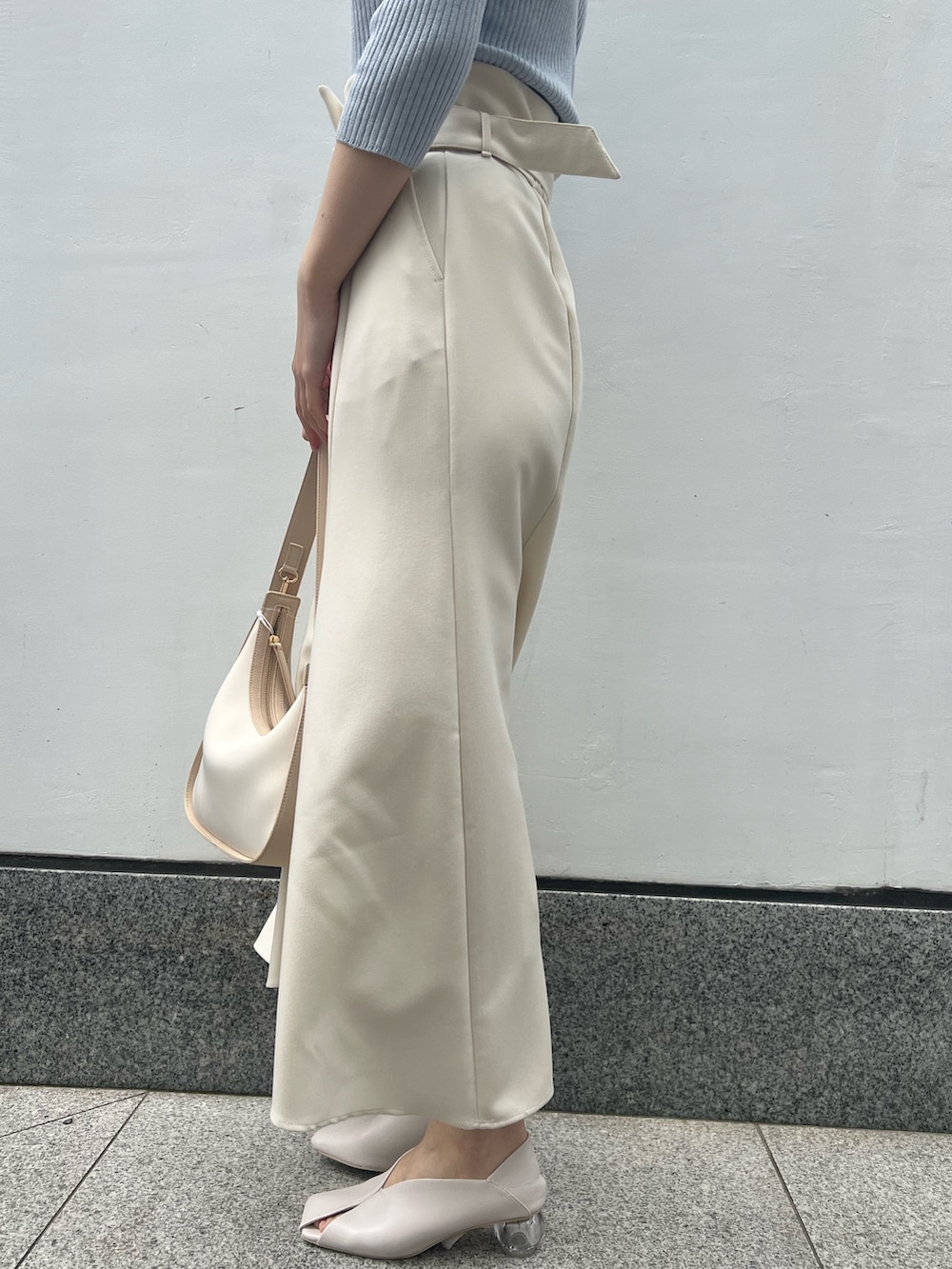 ホワイト系のパンプス、ベージュ系のハンドバッグ、ブルー系のニット/セーターを着用したレディースの春コーディネートの6枚目の写真