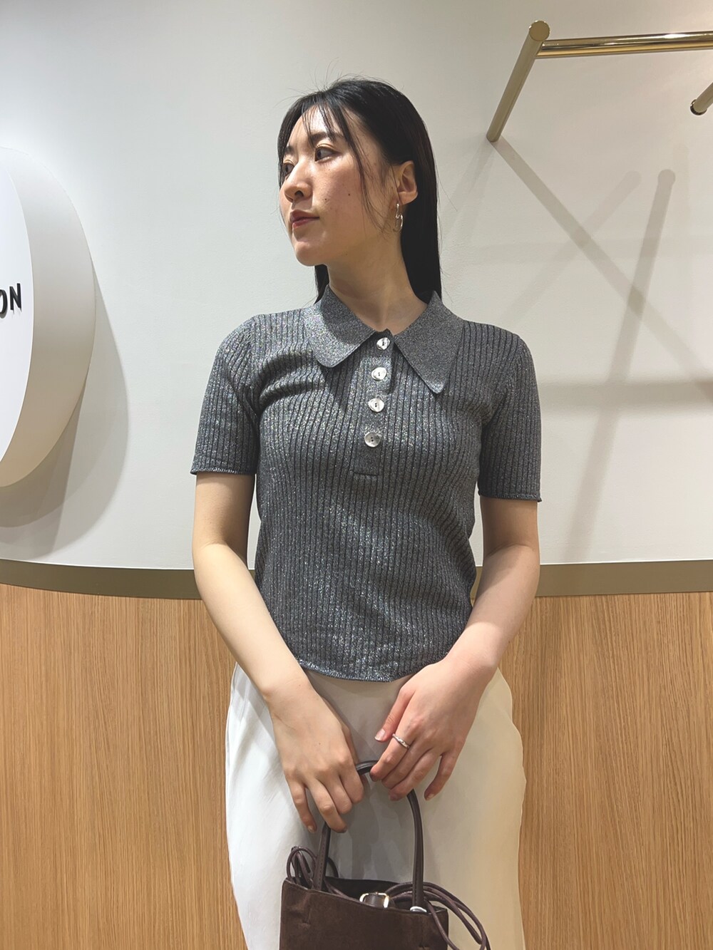 グレー系のニット/セーター、ブラック系のパンプス、ブラウン系のハンドバッグを着用したレディースの春コーディネートの4枚目の写真