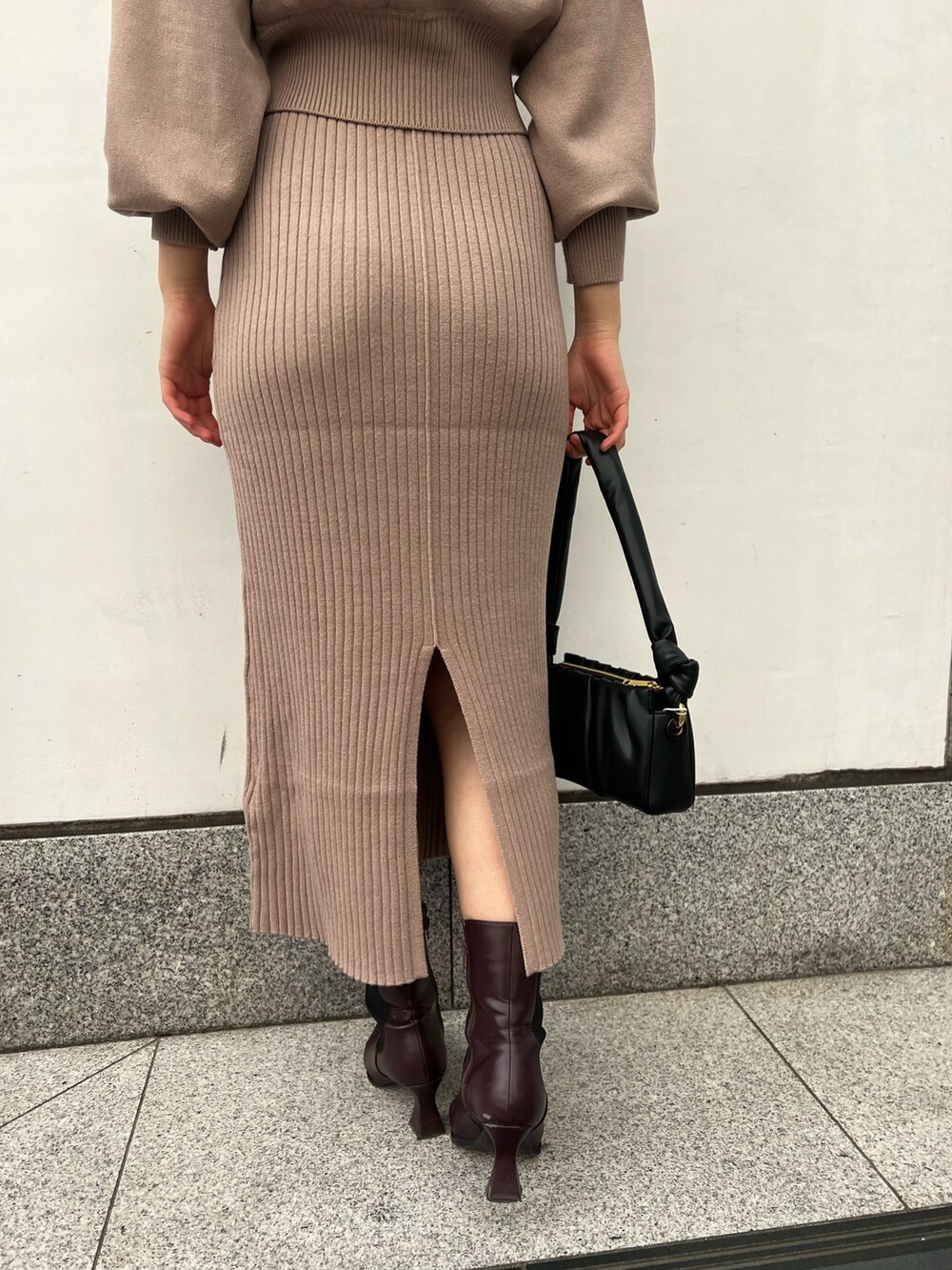 レッド系のブーツ、ブラック系のハンドバッグ、ベージュ系のワンピースを着用したレディースの冬コーディネートの10枚目の写真