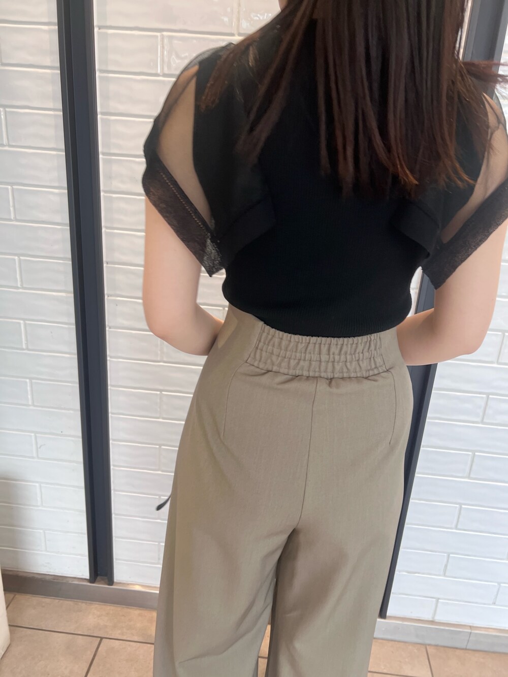 ブラウン系のその他パンツ、ブラック系のニット/セーター、ブラック系のサンダルを着用したレディースの春コーディネートの6枚目の写真