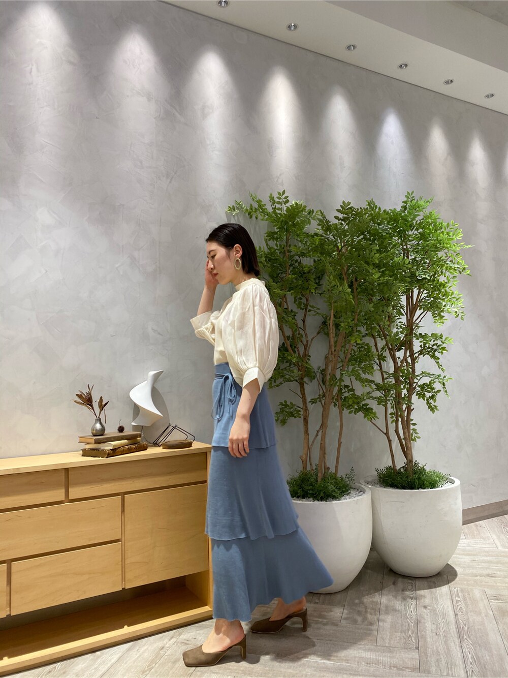 ブルー系のスカート、ホワイト系のニット/セーター、ベージュ系のサンダルを着用したレディースの春コーディネートの4枚目の写真