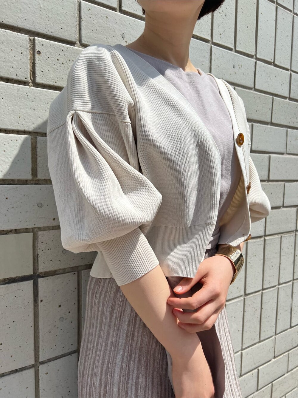 ベージュ系のワンピース、ホワイト系のカーディガン/ボレロ、ゴールド系のバングル/リストバンドを着用したレディースの春コーディネートの5枚目の写真