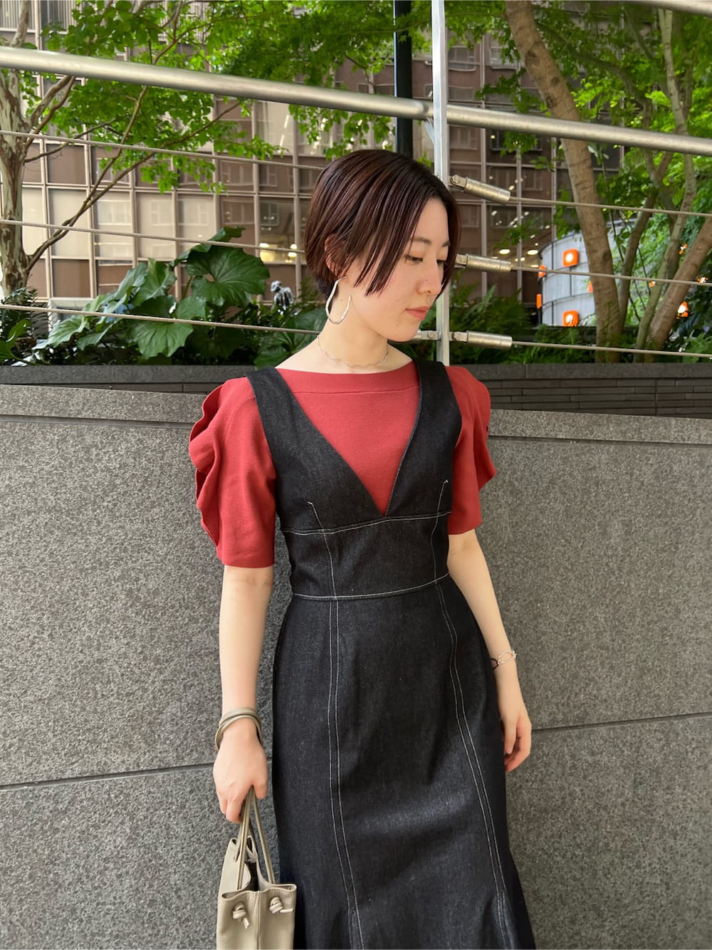 ベージュ系のハンドバッグ、ブラック系のワンピース、オレンジ系のニット/セーターを着用したレディースの夏コーディネートの3枚目の写真