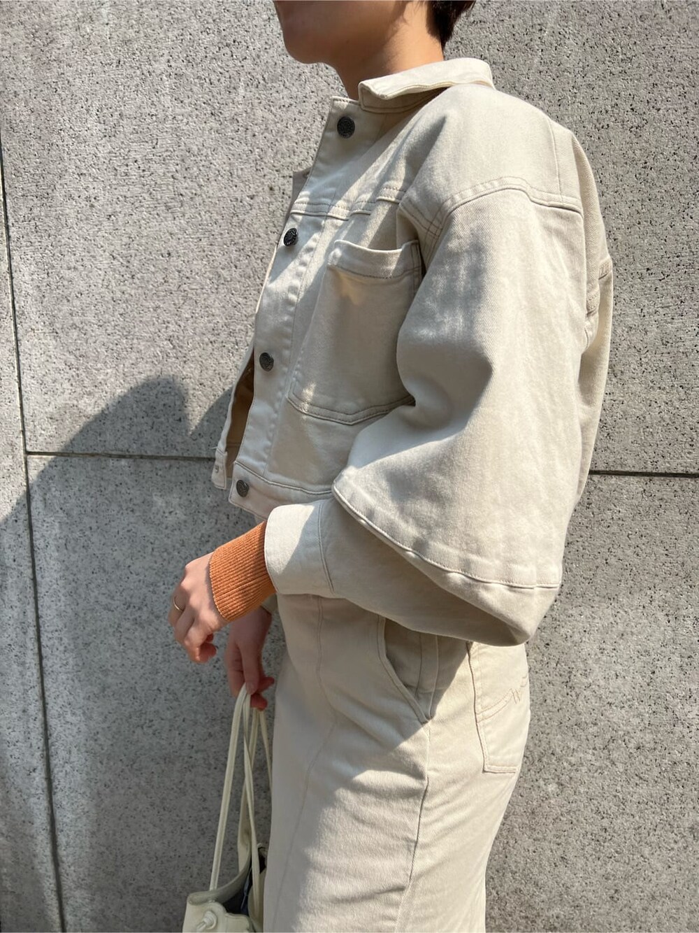 ホワイト系のハンドバッグ、ホワイト系のブルゾン、ホワイト系のスカートを着用したレディースの春コーディネートの6枚目の写真