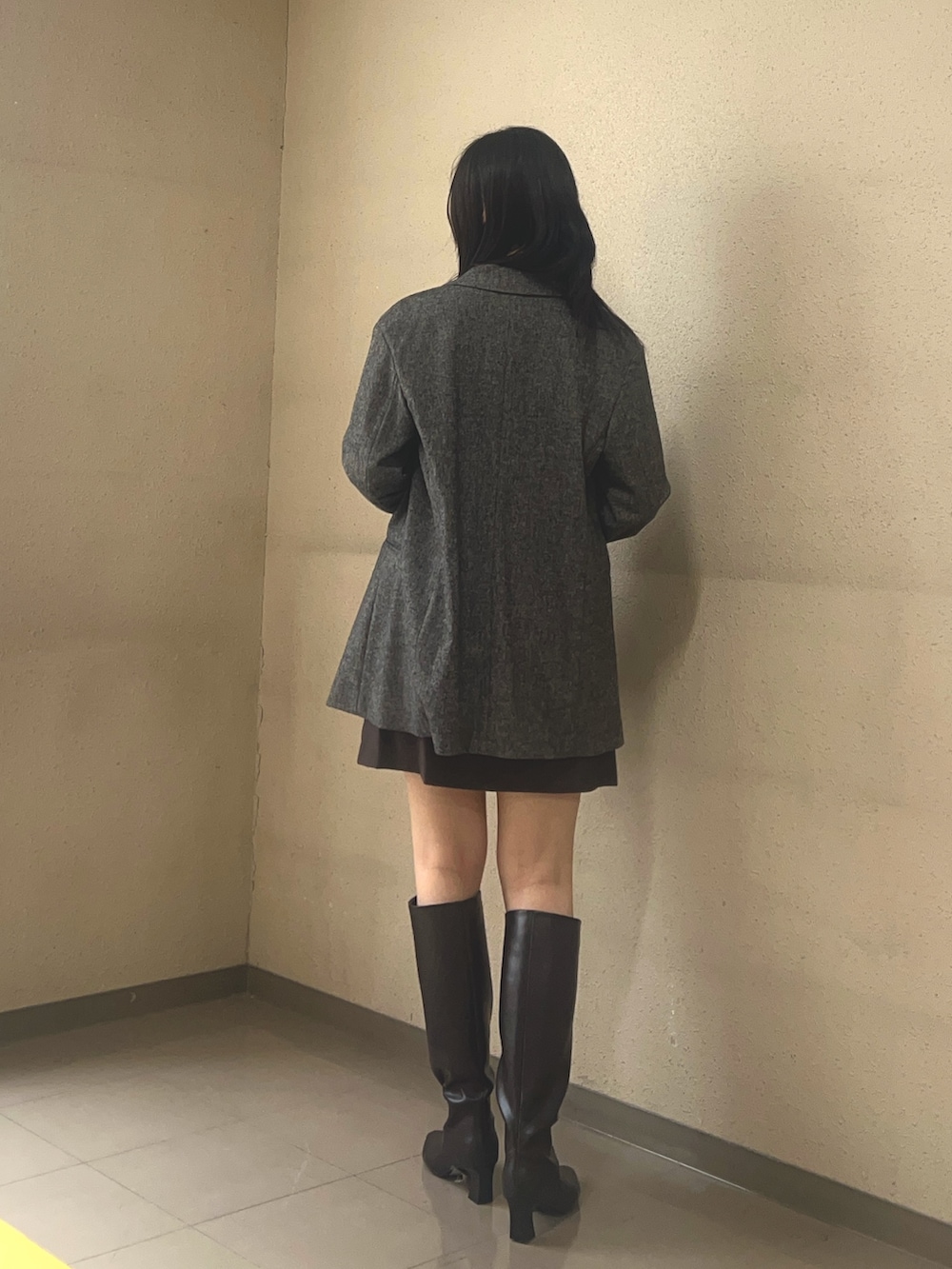 ブラウン系のブーツ、ブラック系のスカート、グレー系のテーラードジャケットを着用したレディースの秋コーディネートの2枚目の写真