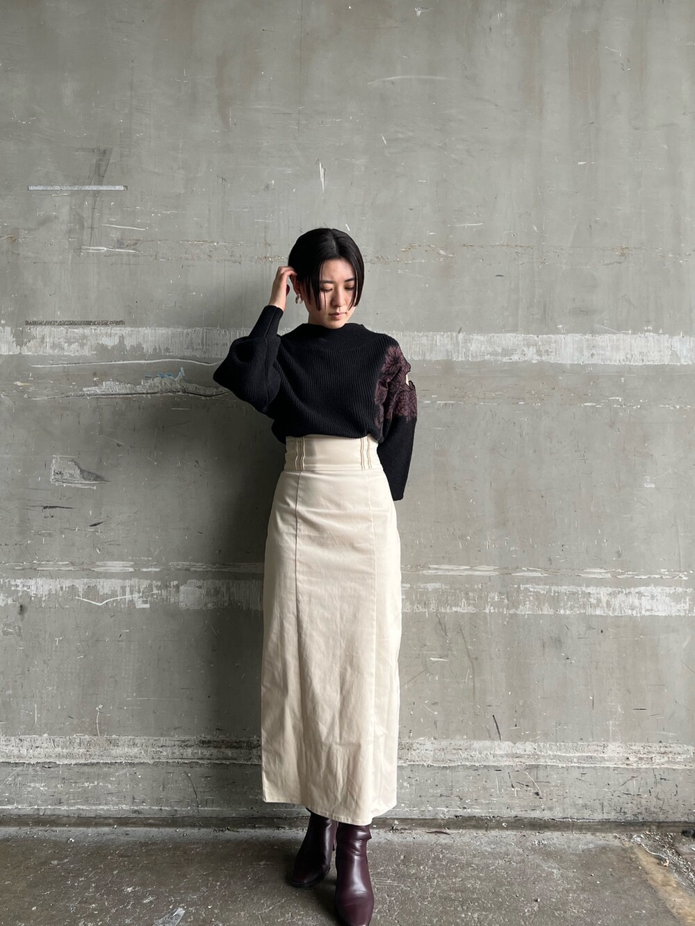 レッド系のブーツ、ホワイト系のスカート、ブラウン系のブルゾンを着用したレディースの冬コーディネートの3枚目の写真