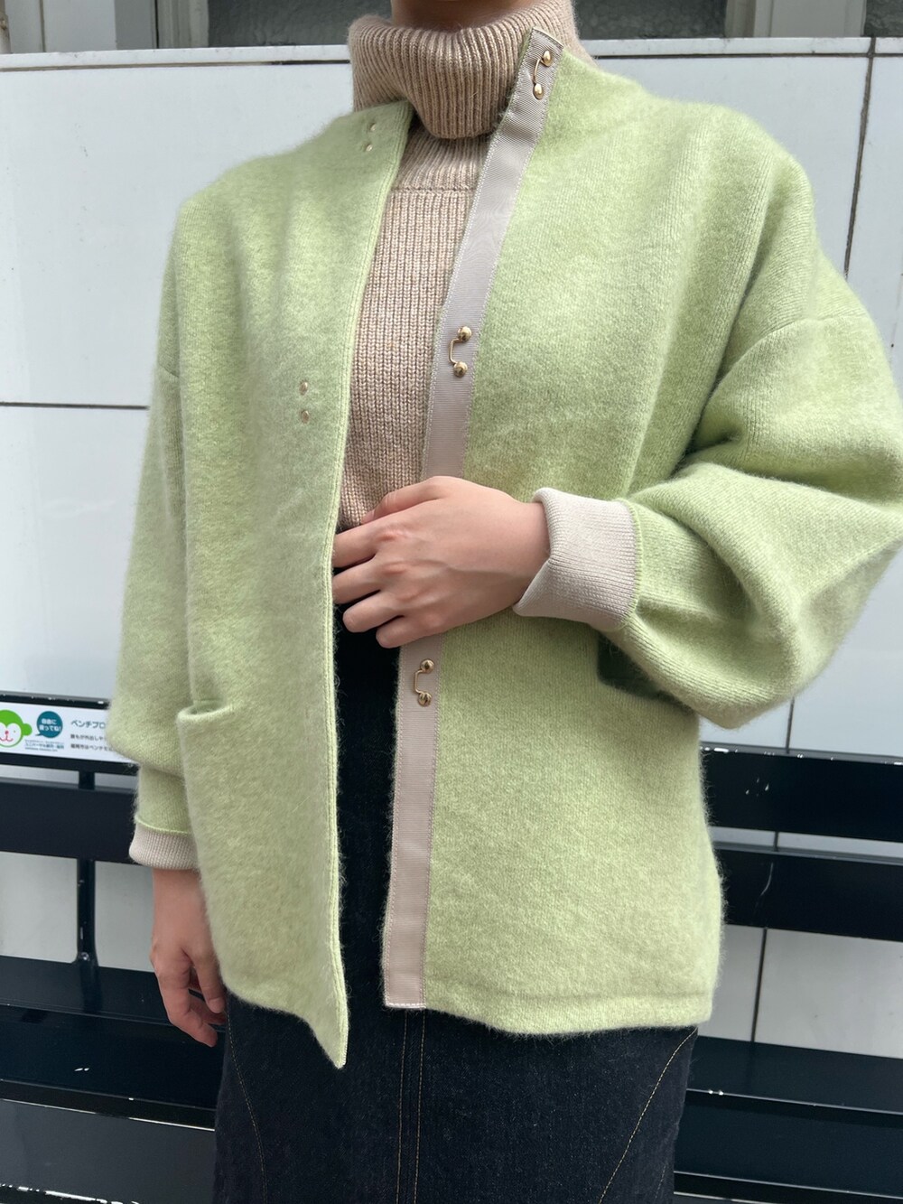 ベージュ系のスニーカー、グリーン系のカーディガン/ボレロ、ブラック系のデニムスカートを着用したレディースの秋コーディネートの5枚目の写真