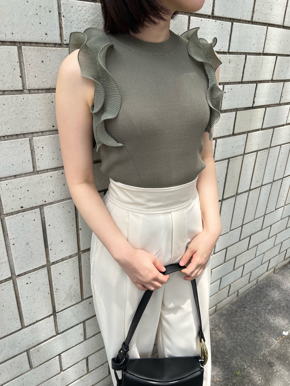 グリーン系のニット/セーター、ホワイト系のその他パンツ、ブラック系のサンダルを着用したレディースの春コーディネートの3枚目の写真