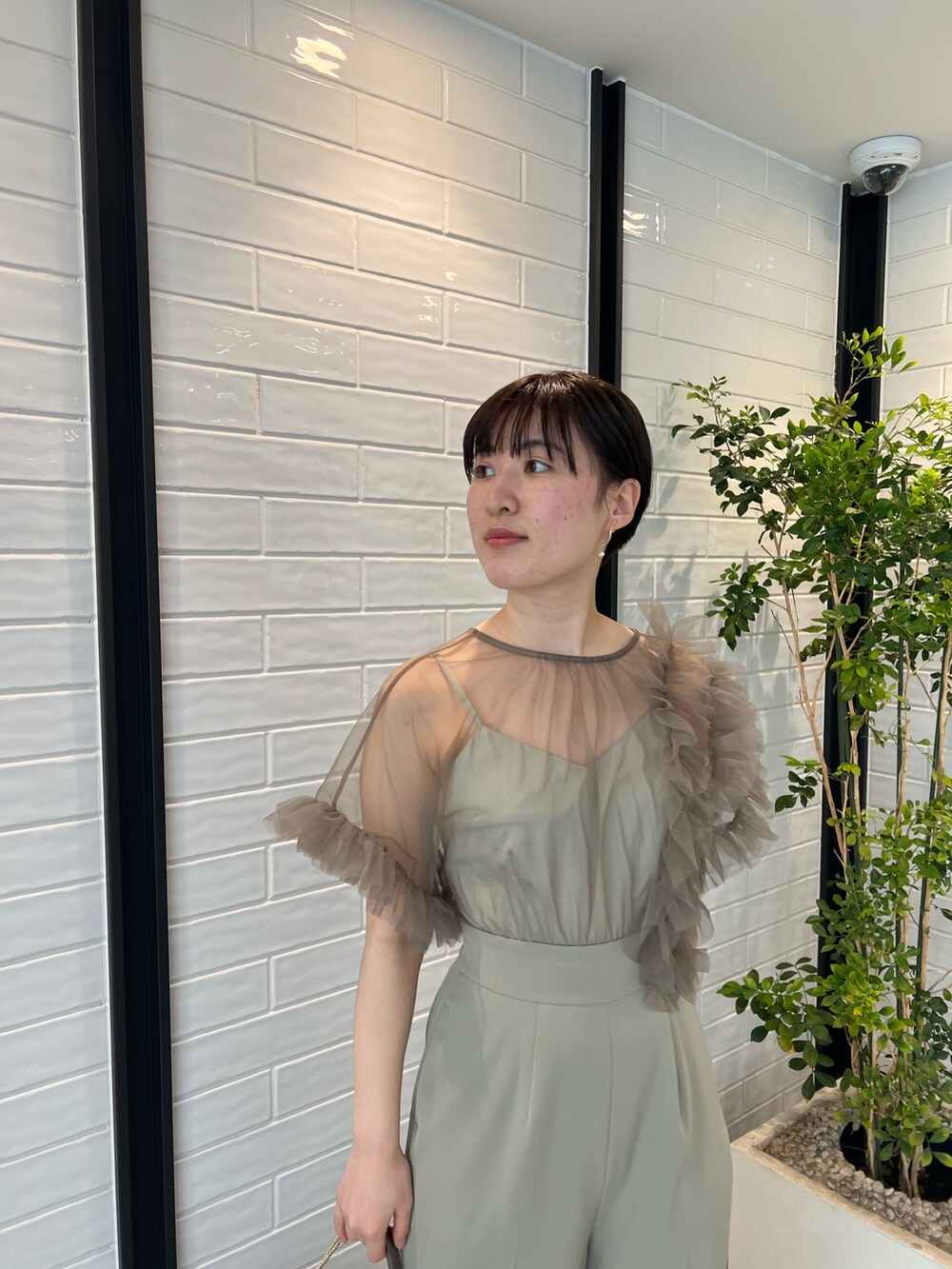 シルバー系のパンプス、シルバー系のハンドバッグ、グリーン系のパンツドレスを着用したレディースの春コーディネートの4枚目の写真