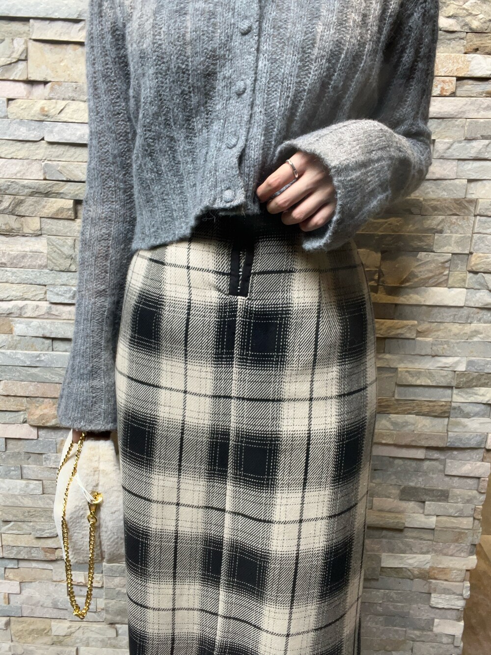 グレー系のニット/セーター、ベージュ系のスカート、ブラック系のブーツを着用したレディースの秋コーディネートの4枚目の写真