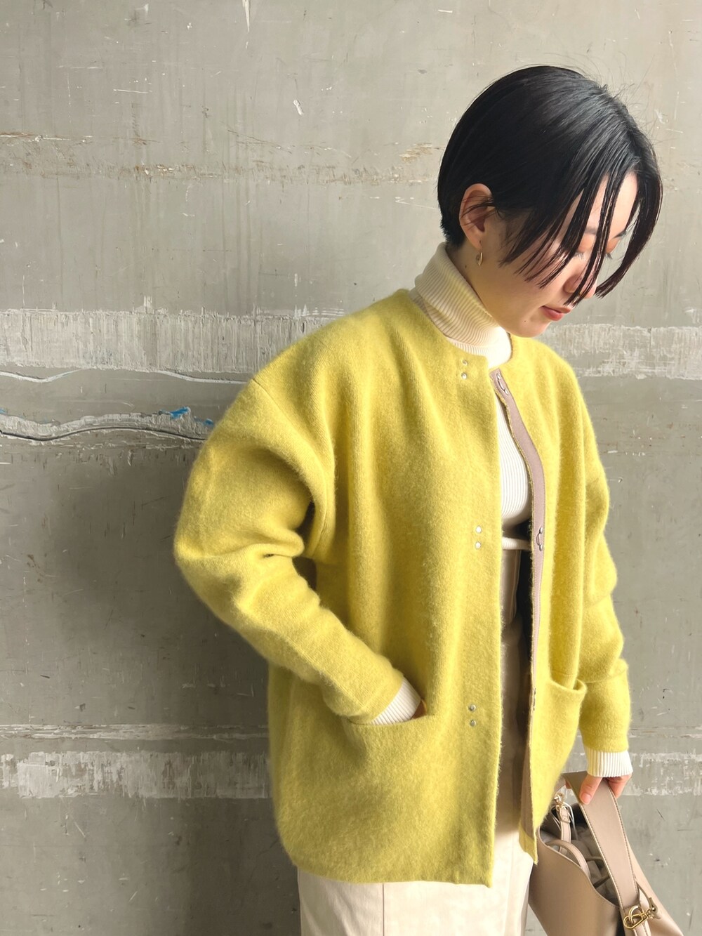 イエロー系のカーディガン/ボレロ、ベージュ系のブーツ、ホワイト系のニット/セーターを着用したレディースの秋コーディネートの4枚目の写真