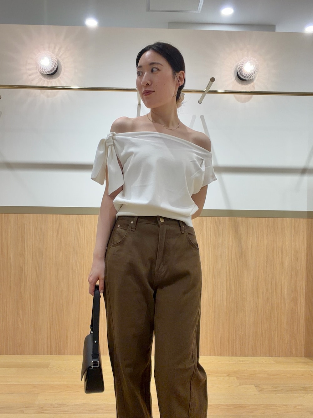 ブラウン系のデニムパンツ、オレンジ系のサンダル、ホワイト系のニット/セーターを着用したレディースの夏コーディネートの4枚目の写真