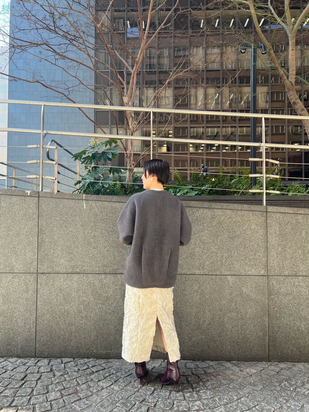 グレー系のカーディガン/ボレロ、ベージュ系のスカート、ホワイト系のニット/セーターを着用したレディースの冬コーディネートの2枚目の写真