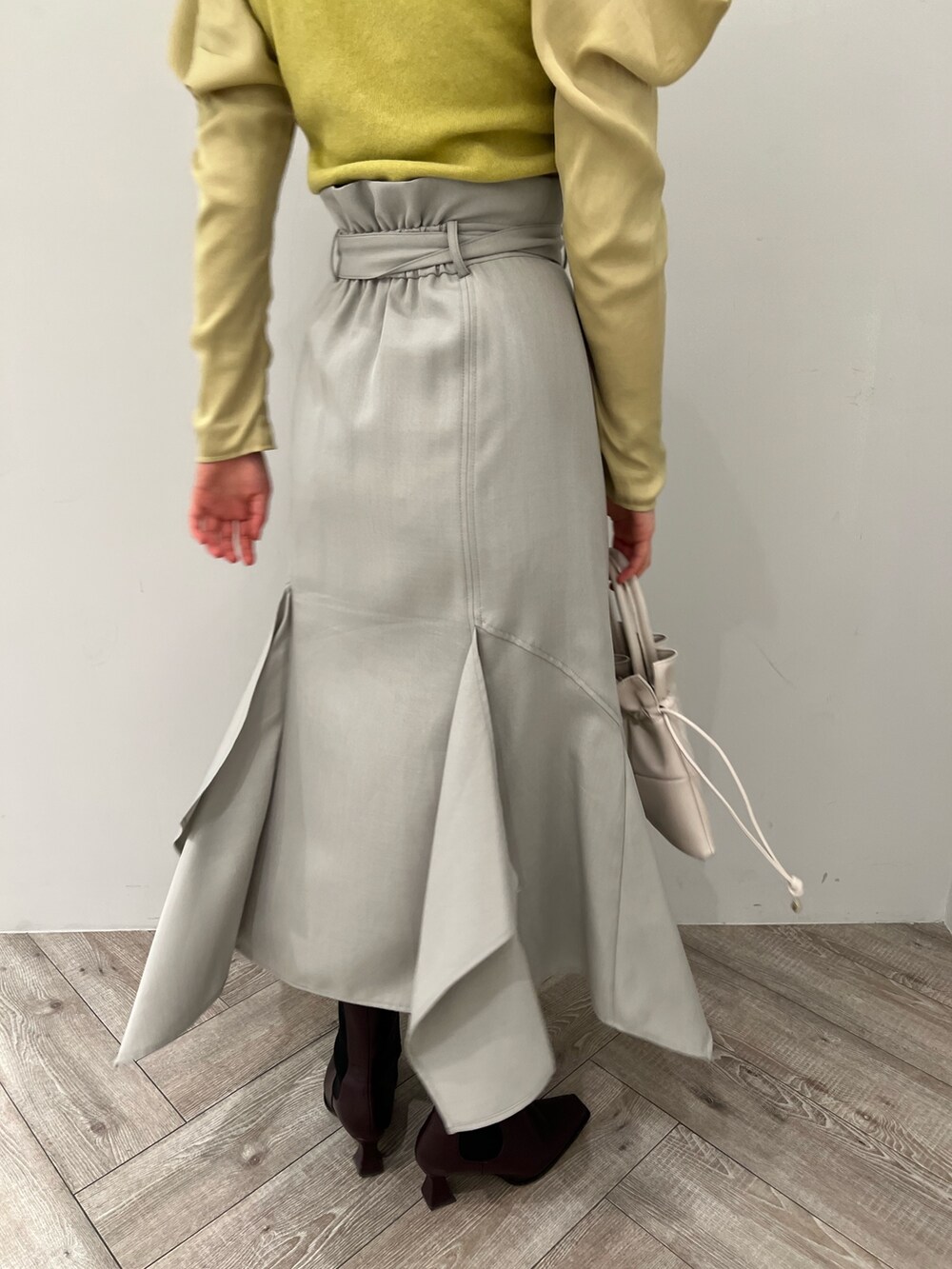 ブラック系のブーツ、ホワイト系のハンドバッグ、グリーン系のスカートを着用したレディースの冬コーディネートの8枚目の写真