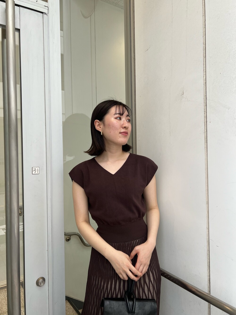 ブラック系のサンダル、ブラック系のハンドバッグ、ブラウン系のワンピースを着用したレディースの夏コーディネートの4枚目の写真