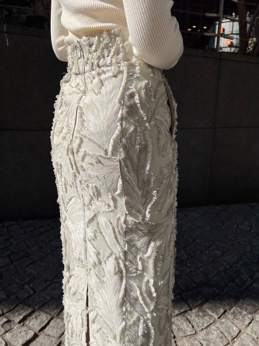 グレー系のカーディガン/ボレロ、ベージュ系のスカート、ホワイト系のニット/セーターを着用したレディースの冬コーディネートの9枚目の写真