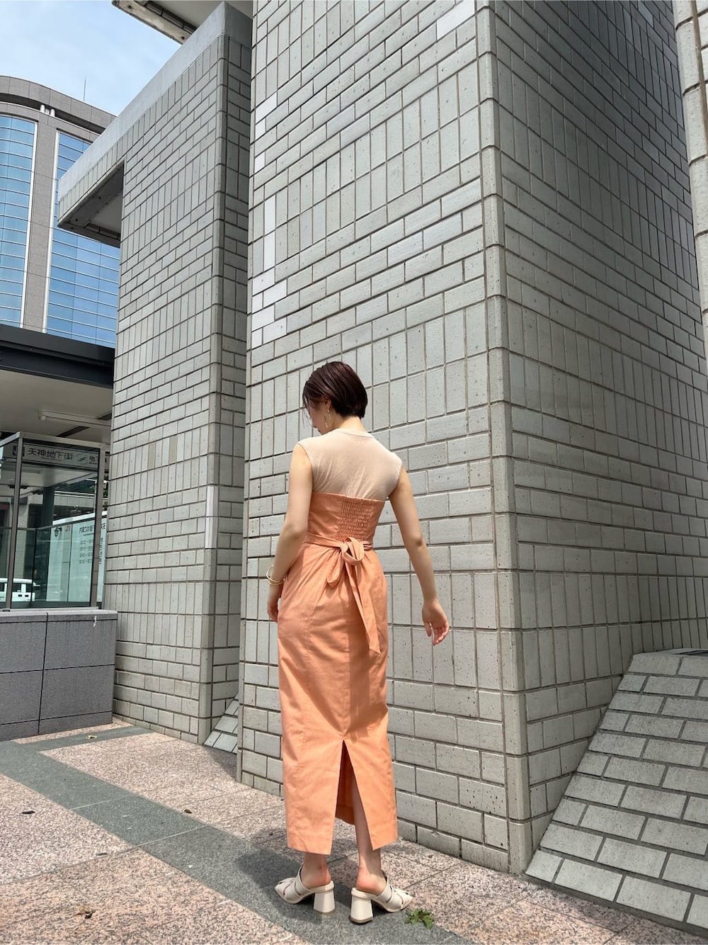 ホワイト系のブルゾン、オレンジ系のワンピース、ホワイト系のサンダルを着用したレディースの春コーディネートの4枚目の写真