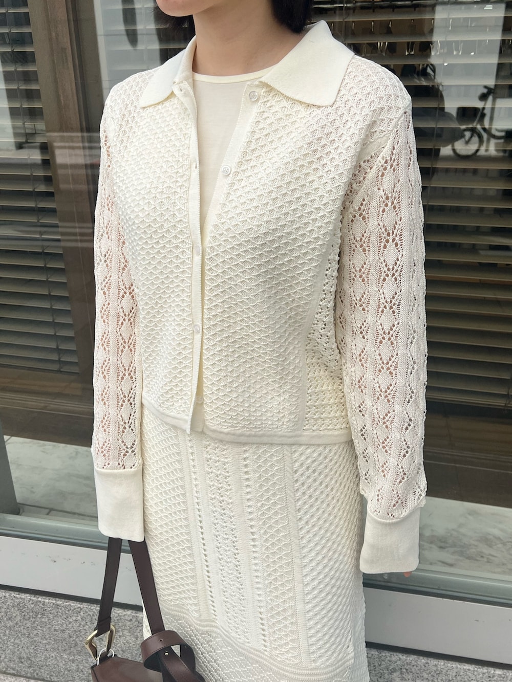 ブラウン系のショルダーバッグ、ホワイト系のカーディガン/ボレロ、ホワイト系のTシャツ/カットソーを着用したレディースの春コーディネートの6枚目の写真