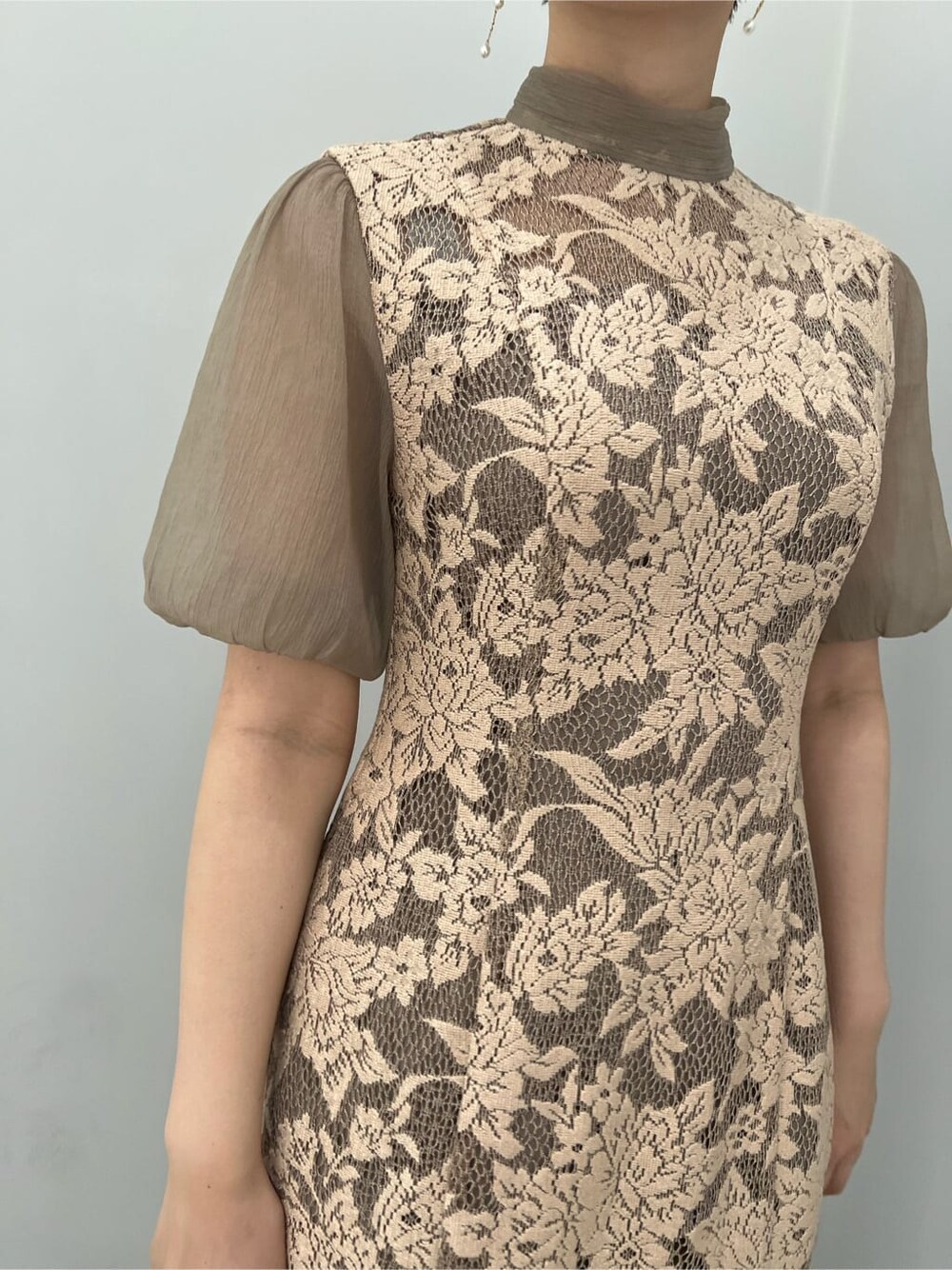 ゴールド系のクラッチバッグ、ゴールド系のパンプス、ベージュ系のドレスを着用したレディースの夏コーディネートの3枚目の写真