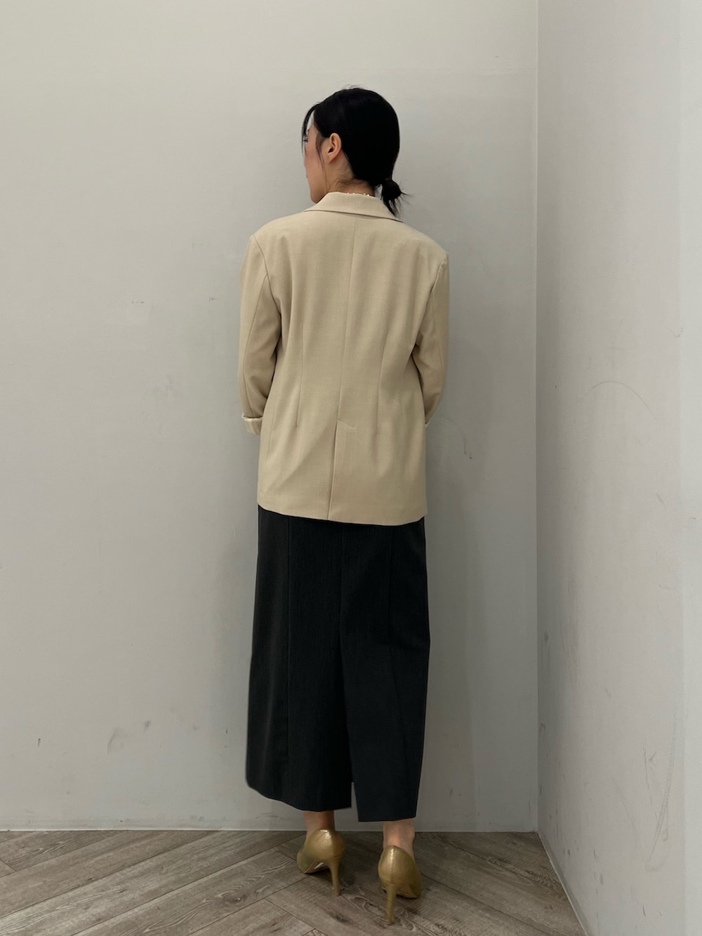 ゴールド系のパンプス、グレー系のドレス、ベージュ系のテーラードジャケットを着用したレディースの秋コーディネートの3枚目の写真