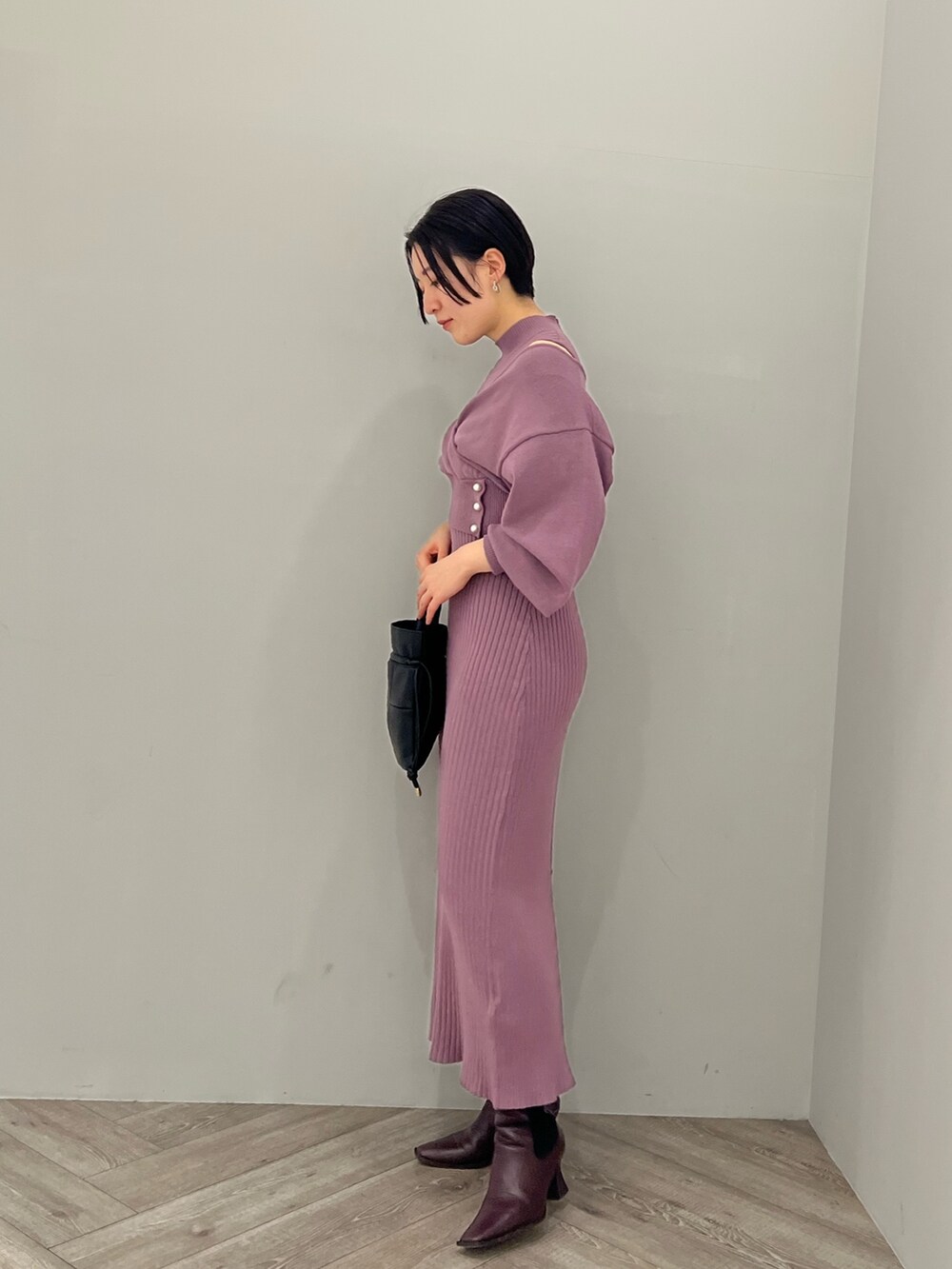 レッド系のブーツ、ブラック系のハンドバッグ、パープル系のワンピースを着用したレディースの冬コーディネートの2枚目の写真