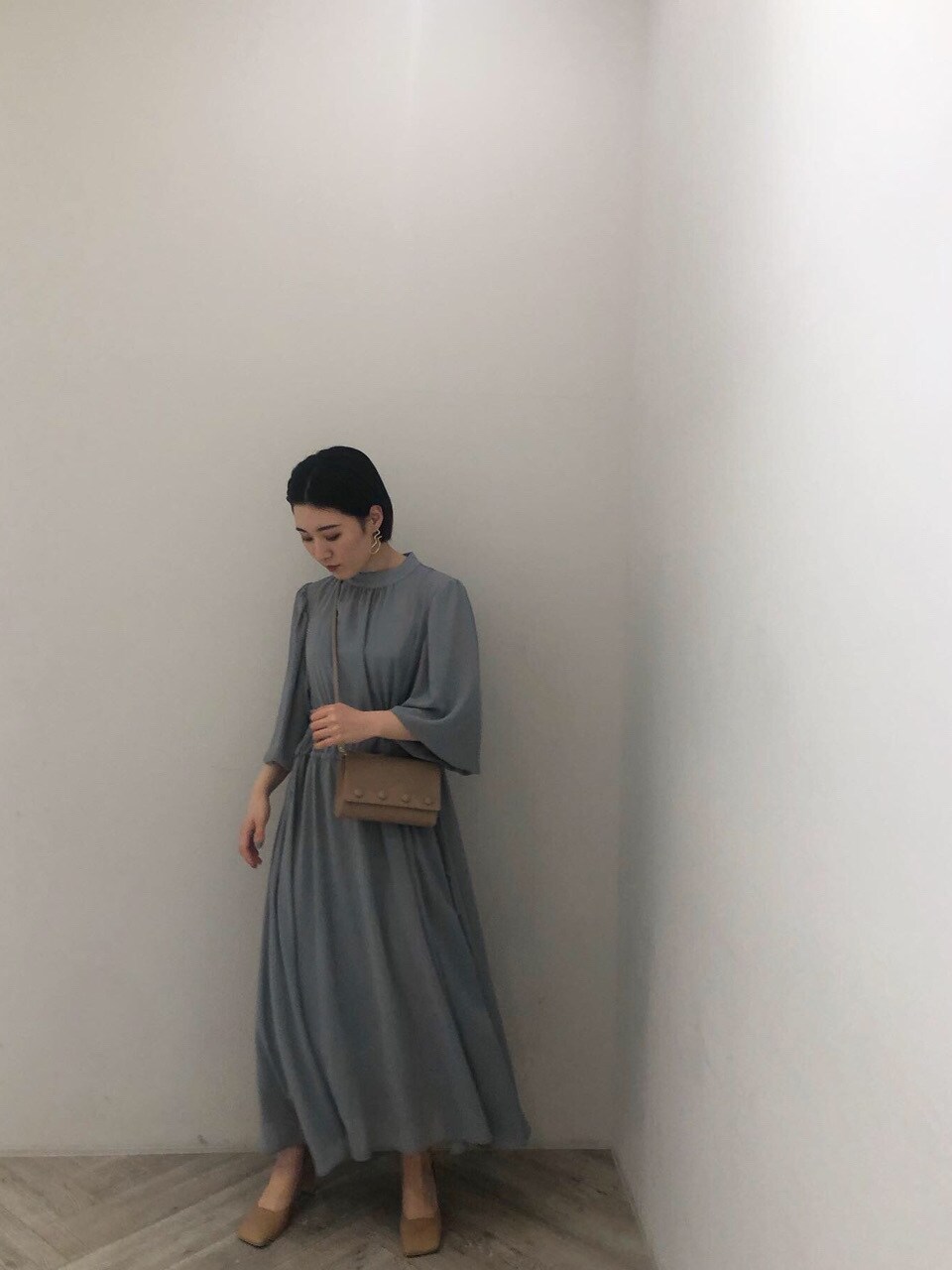 ベージュ系のハンドバッグ、ブルー系のワンピースを着用したレディースの冬コーディネートの2枚目の写真