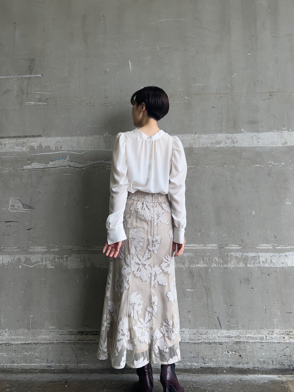 ベージュ系のスカート、ホワイト系のシャツ/ブラウス、ゴールド系のピアス(両耳用)を着用したレディースの秋コーディネートの2枚目の写真