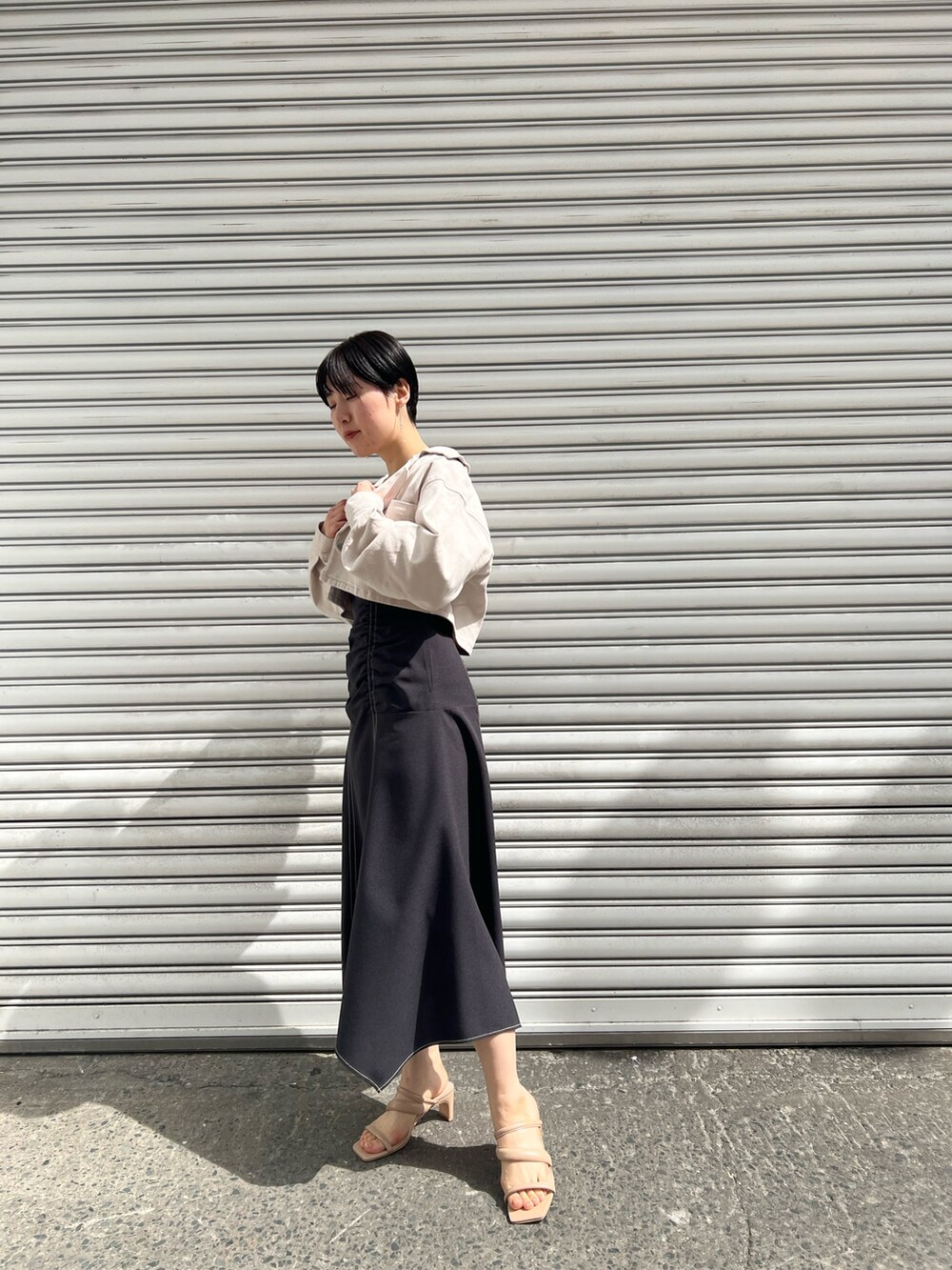 ベージュ系のサンダル、ブラック系のワンピース、ベージュ系のテーラードジャケットを着用したレディースの春コーディネートの2枚目の写真