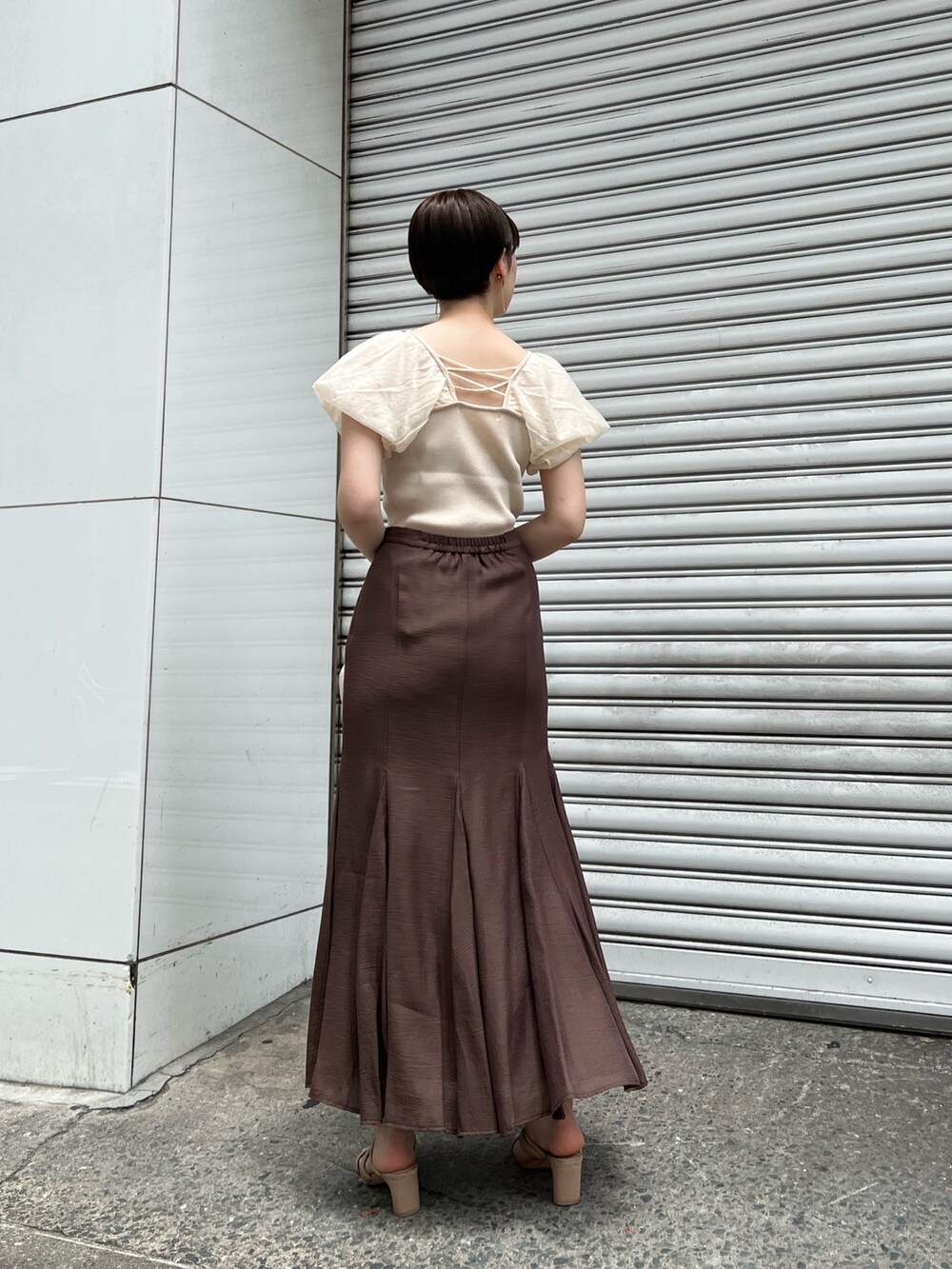 ベージュ系のサンダル、ブラウン系のスカート、ホワイト系のハンドバッグを着用したレディースの夏コーディネートの3枚目の写真