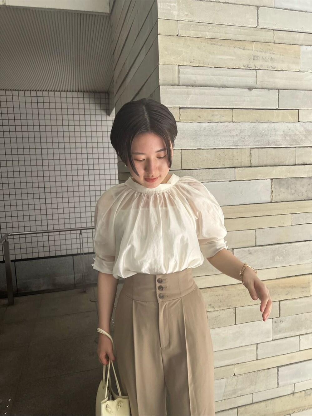 ホワイト系のハンドバッグ、ブラウン系のパンプス、ホワイト系のシャツ/ブラウスを着用したレディースの夏コーディネートの4枚目の写真