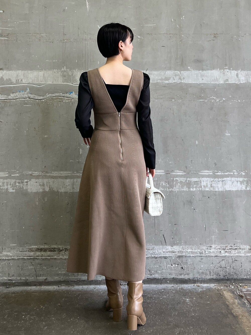 ブラック系のニット/セーター、ホワイト系のショルダーバッグ、ベージュ系のブーツを着用したレディースの冬コーディネートの2枚目の写真