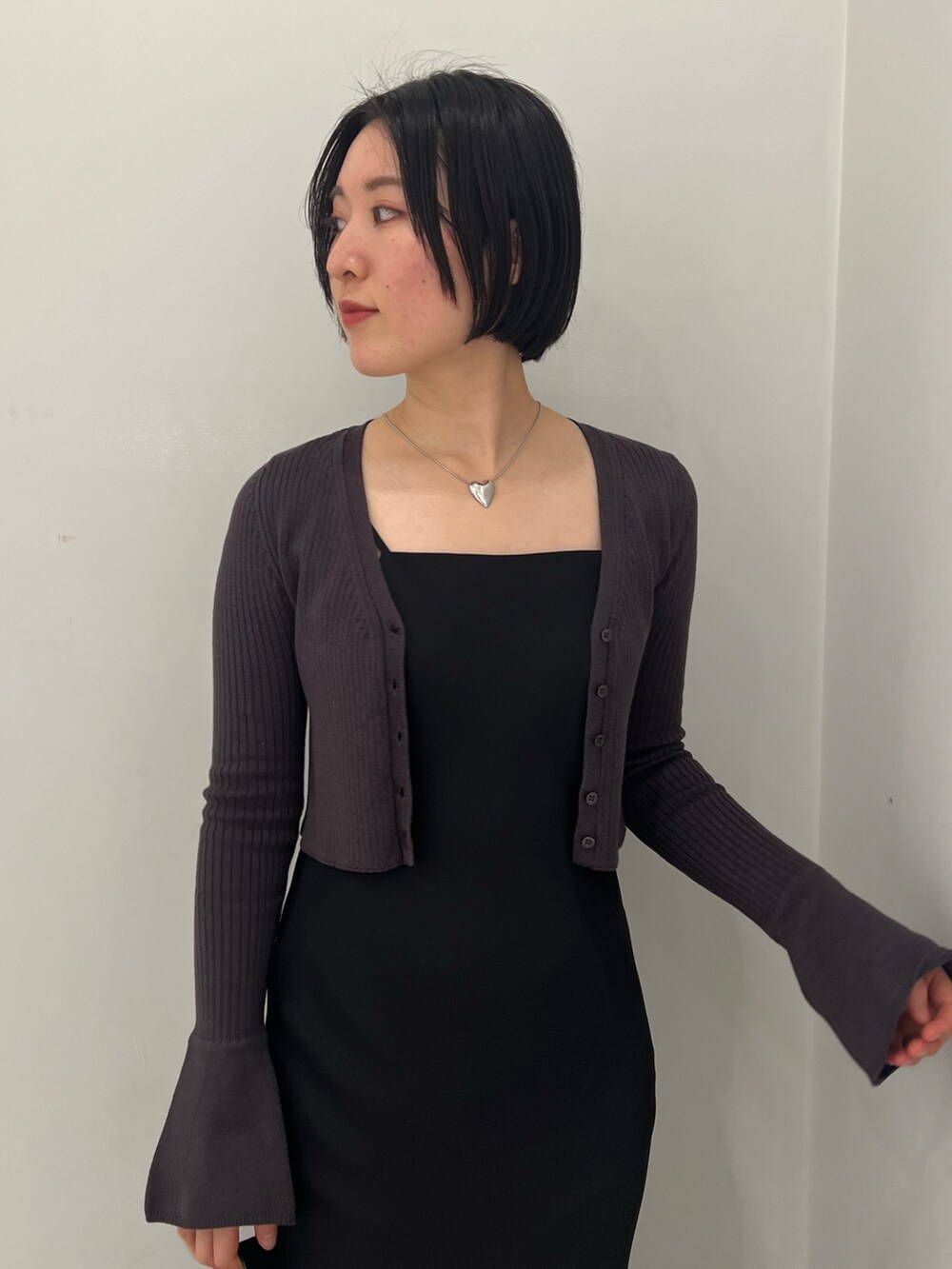 ブラック系のハンドバッグ、シルバー系のパンプス、ブラック系のワンピースを着用したレディースの冬コーディネートの2枚目の写真