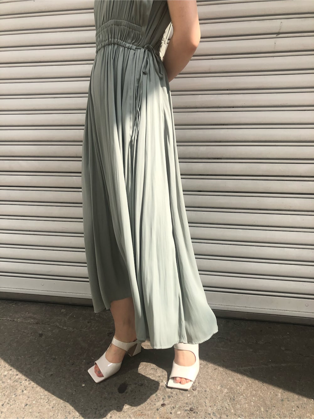 ホワイト系のサンダル、グリーン系のワンピース、ベージュ系のハンドバッグを着用したレディースの春コーディネートの2枚目の写真