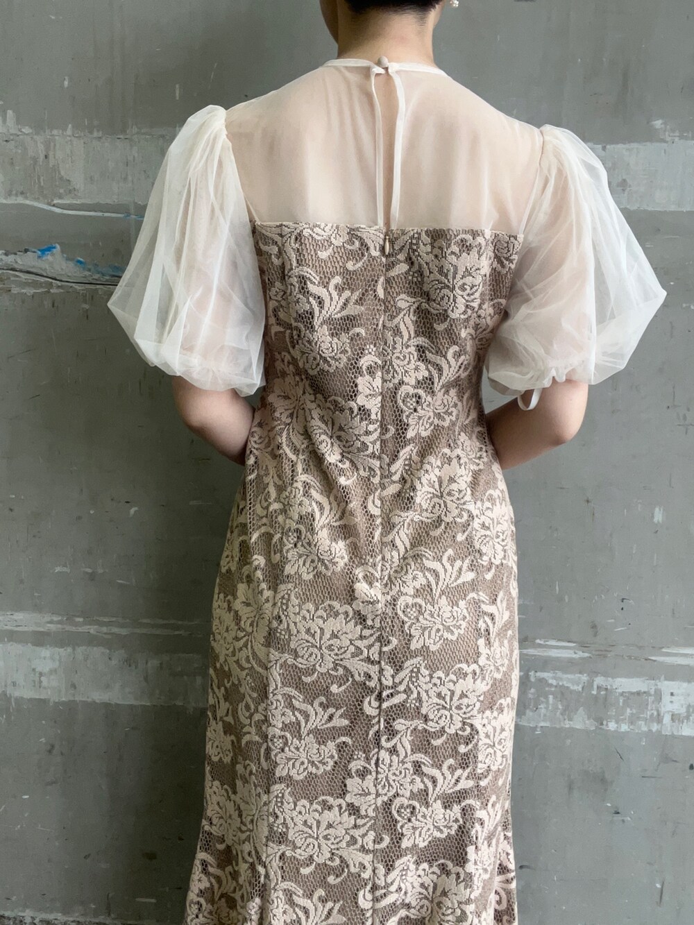 ベージュ系のドレス、ブラウン系のクラッチバッグ、ゴールド系のパンプスを着用したレディースの秋コーディネートの7枚目の写真