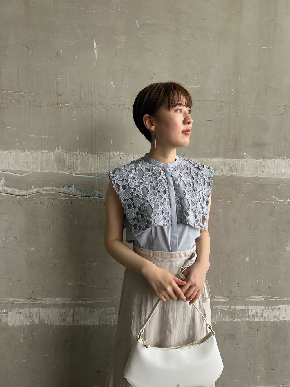 ベージュ系のサンダル、ホワイト系のハンドバッグ、グレー系のスカートを着用したレディースの夏コーディネートの3枚目の写真