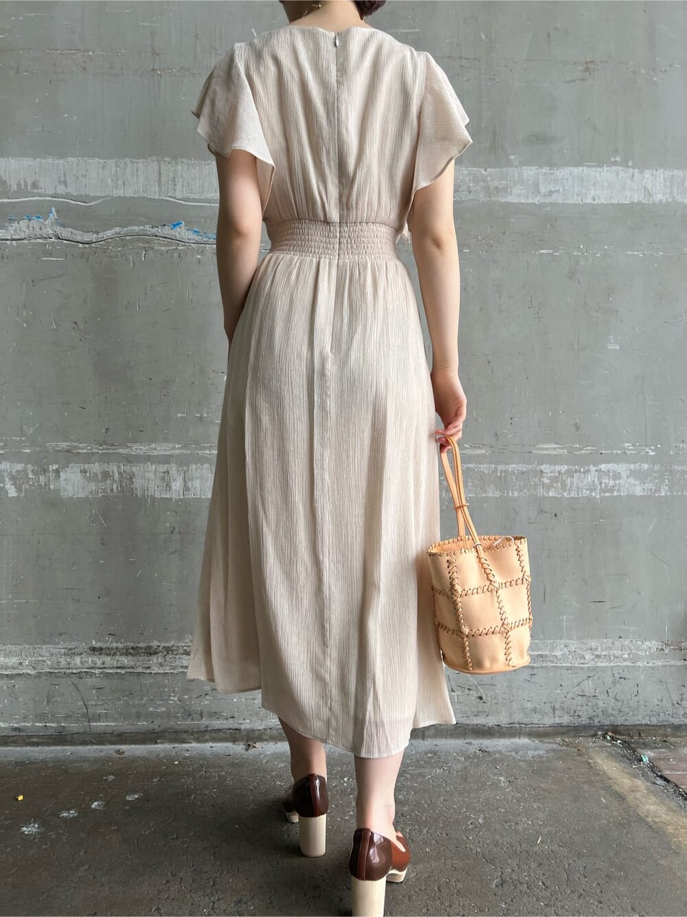 ホワイト系のワンピース、ブラウン系のパンプス、オレンジ系のショルダーバッグを着用したレディースの春コーディネートの5枚目の写真