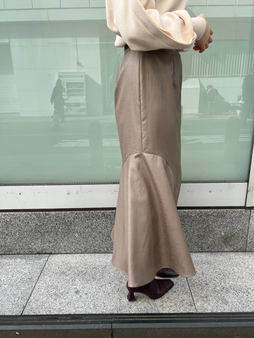 レッド系のブーツ、ベージュ系のスカート、ホワイト系のニット/セーターを着用したレディースの冬コーディネートの9枚目の写真