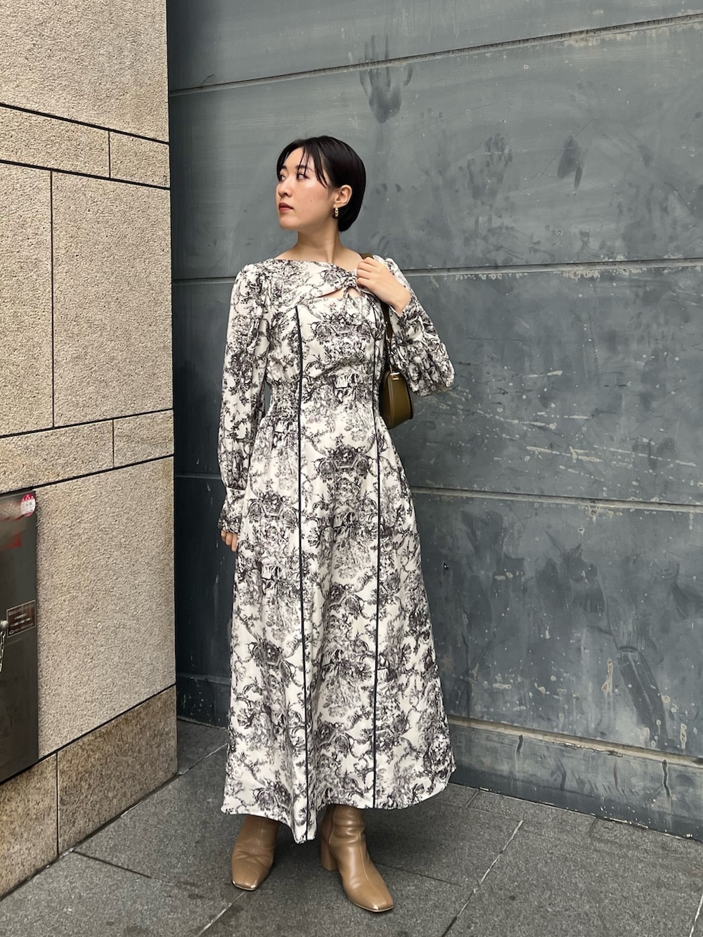 ホワイト系のノーカラーコート、ホワイト系のワンピース、ベージュ系のブーツを着用したレディースの冬コーディネートの2枚目の写真