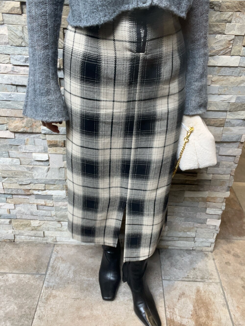 グレー系のニット/セーター、ベージュ系のスカート、ブラック系のブーツを着用したレディースの秋コーディネートの5枚目の写真