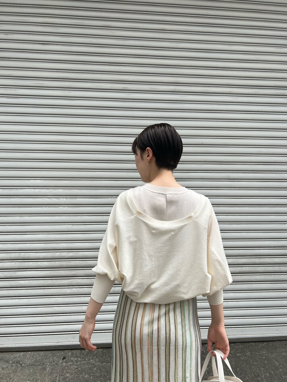 ホワイト系のショルダーバッグ、ベージュ系のサンダル、ホワイト系のワンピースを着用したレディースの春コーディネートの3枚目の写真