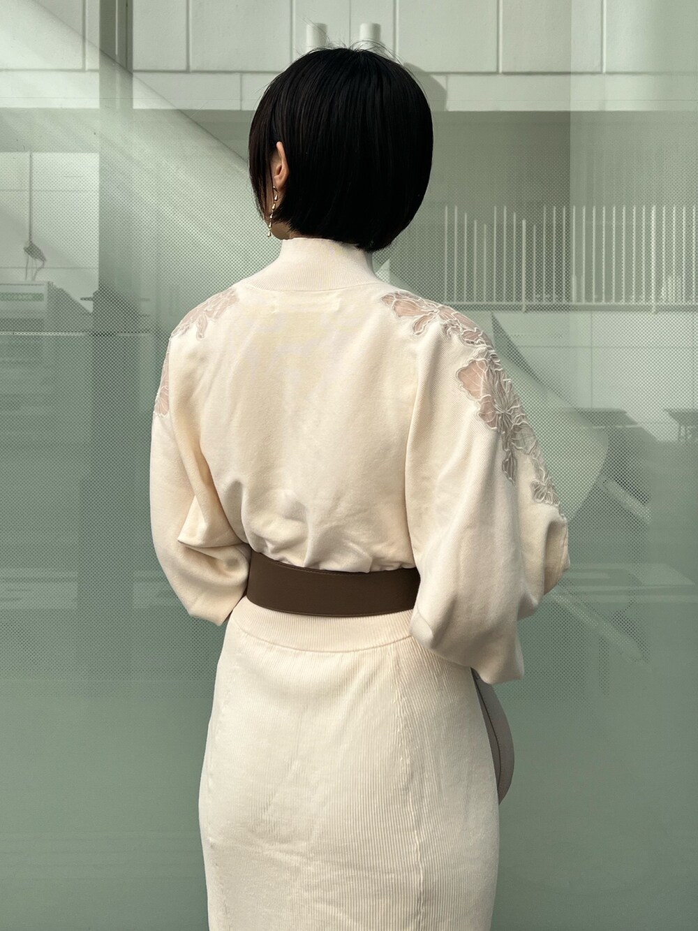 ホワイト系のハンドバッグ、ベージュ系のブーツ、ホワイト系のワンピースを着用したレディースの冬コーディネートの4枚目の写真