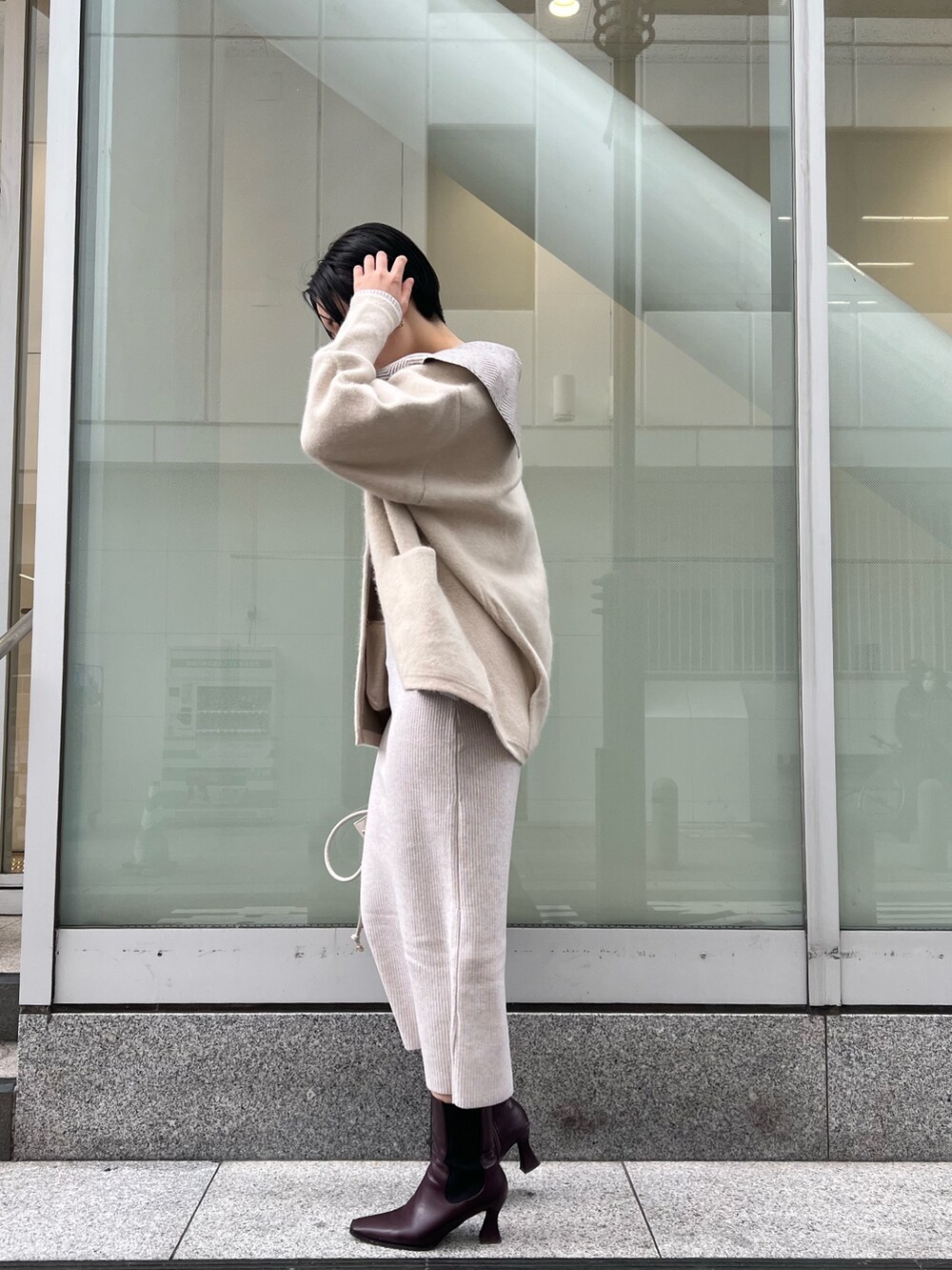 ホワイト系のワンピース、ホワイト系のカーディガン/ボレロ、レッド系のブーツを着用したレディースの冬コーディネートの2枚目の写真