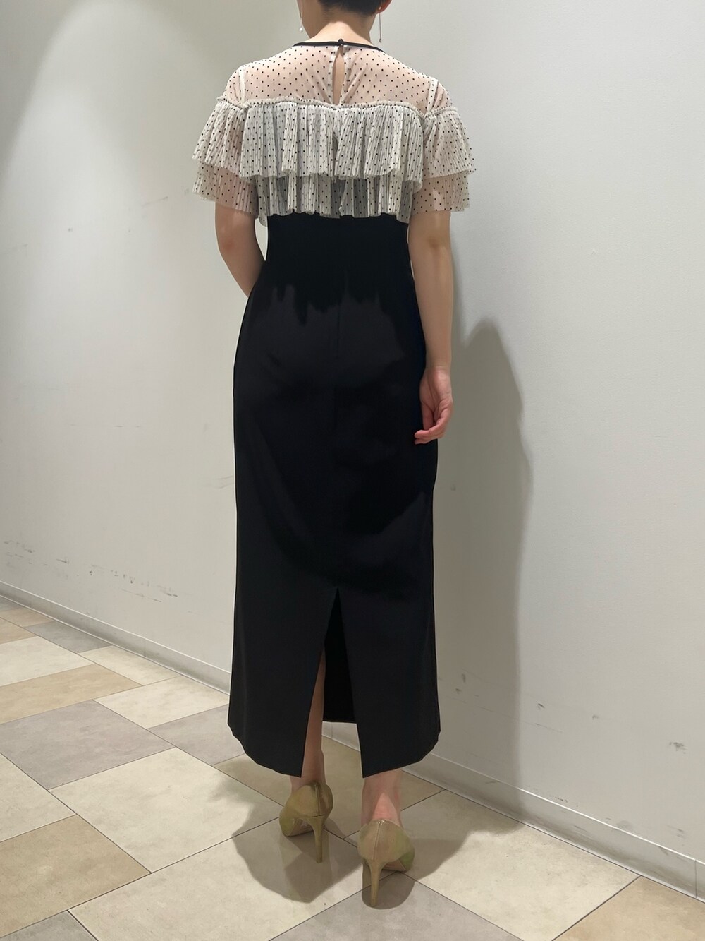 ゴールド系のパンプス、ゴールド系のハンドバッグ、ブラック系のドレスを着用したレディースの夏コーディネートの2枚目の写真