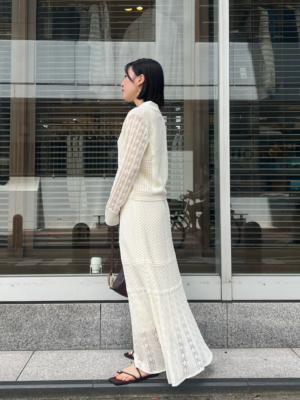 ブラウン系のショルダーバッグ、ホワイト系のカーディガン/ボレロ、ホワイト系のTシャツ/カットソーを着用したレディースの春コーディネートの2枚目の写真