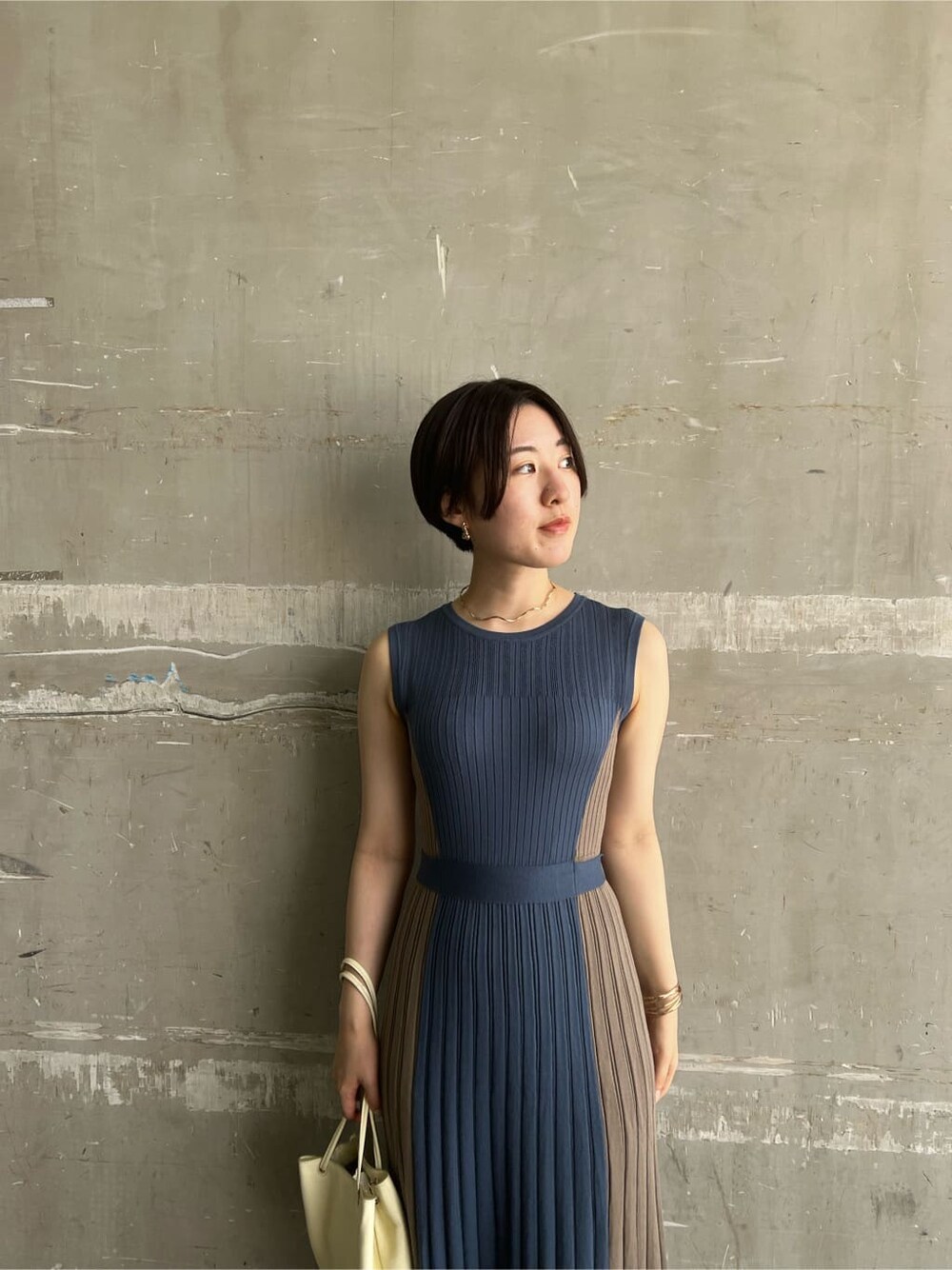 ホワイト系のハンドバッグ、ブルー系のワンピース、ゴールド系のピアス（両耳用）を着用したレディースの夏コーディネートの4枚目の写真