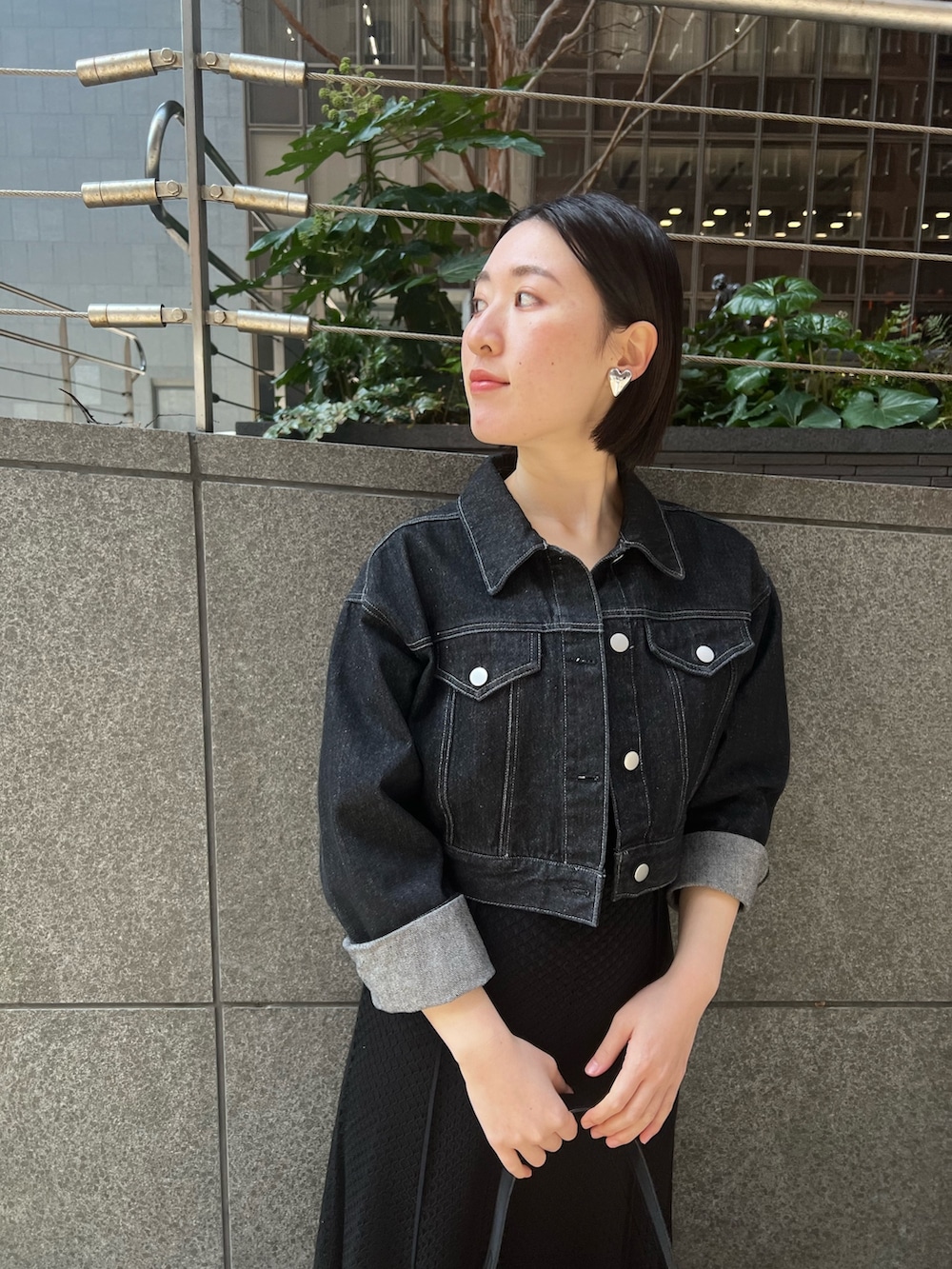 ブラック系のデニムジャケット、ホワイト系のパンプス、ブラック系のハンドバッグを着用したレディースの春コーディネートの2枚目の写真