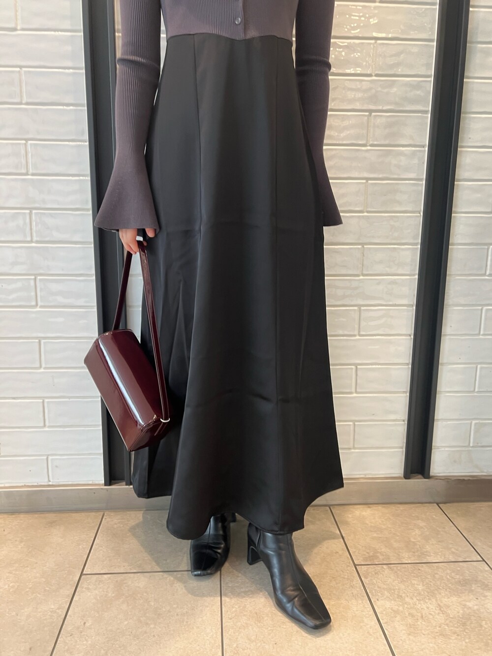 レッド系のショルダーバッグ、ブラック系のブーツ、グレー系のワンピースを着用したレディースの秋コーディネートの6枚目の写真